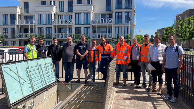 Groep mensen op een rij bij een luik op de parkeerplaats aan de Oosterstraat