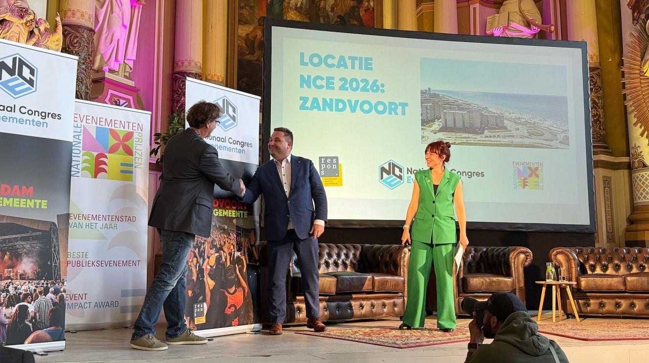 Wethouder Lars Carree schudt de hand van een man op podium Nationaal Congres Evenementen 2026