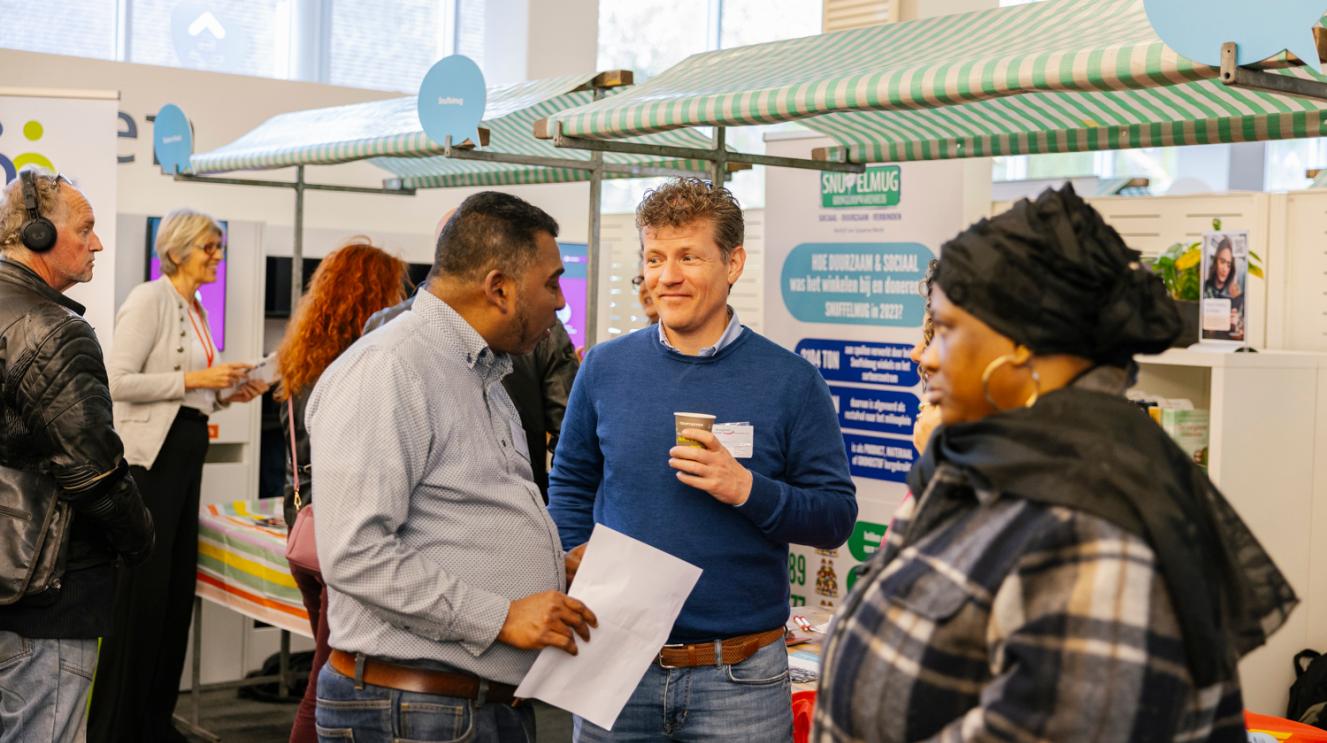 Twee mannen en een vrouw bij een kraampje op de participatiemarkt