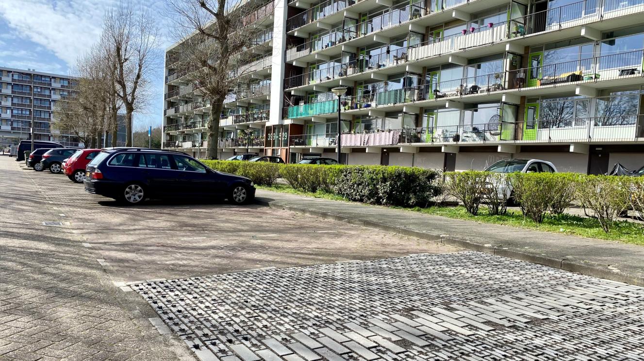 Auto's staan geparkeerd bij een flat naast enkele lege parkeerplekken