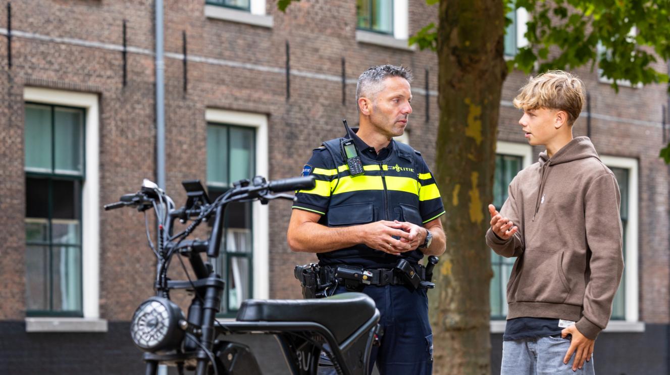 Agent en jongere met fatbike in gesprek.