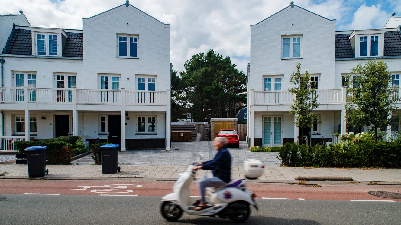 Scooter rijdt voor huizen langs