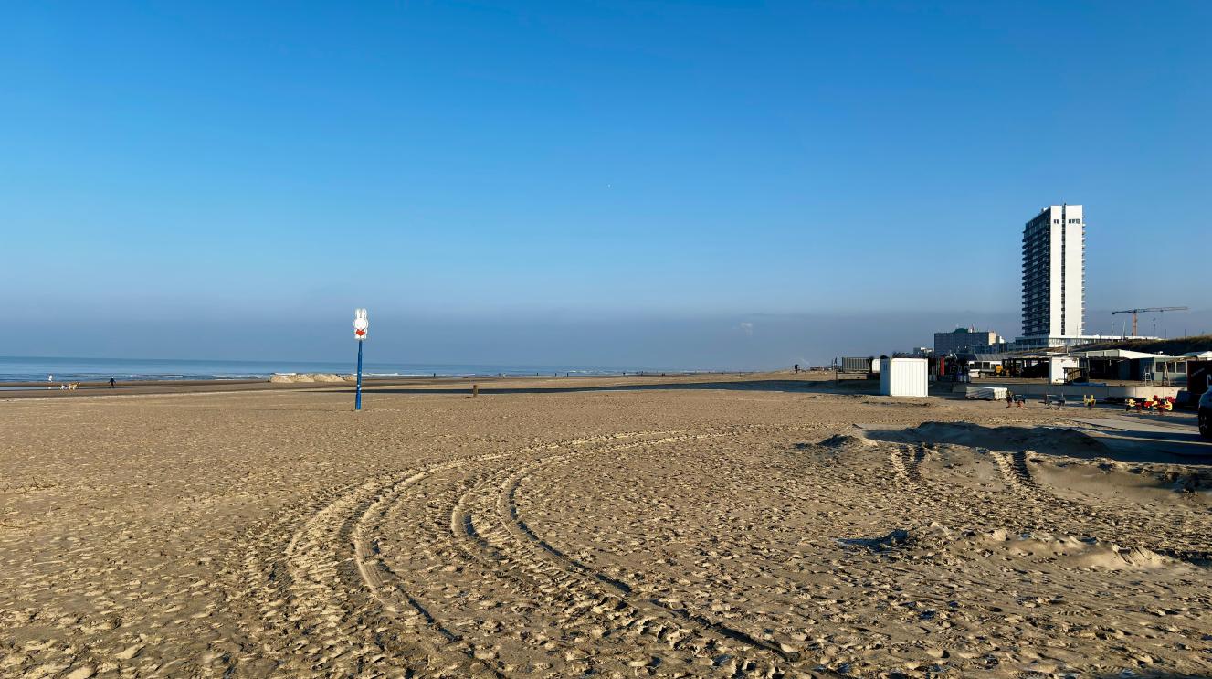 Strandaanzicht met bandensporen in het zand