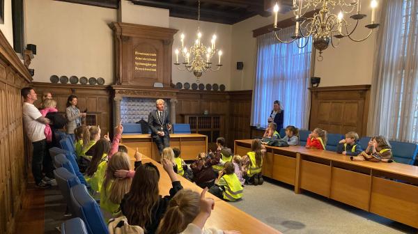 Leerlingen en de burgemeester in de raadzaal. 